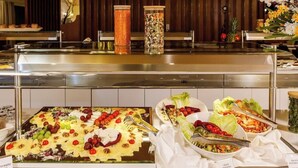 A buffet with various food options, including salads, fruits, and a dessert tray.