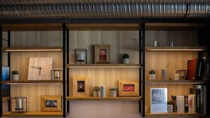 Un interior moderno con estanterías de madera que exhiben libros, marcos con fotografías y objetos decorativos.