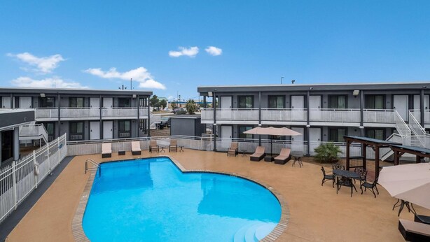 A hotel with a swimming pool, outdoor seating, and a clear blue sky. - Laredo Hotel (Laredo)