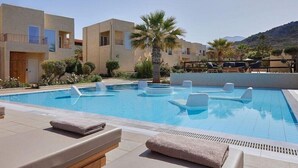 A swimming pool with lounge chairs, a palm tree, and a mountain in the background. - Vasia Sea Retreat - Adults Only (Agios Nikolaos)