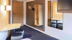 A modern hotel room with a bed, a desk, a mirror, and built-in shelves. - Intercityhotel Kassel (Kassel)