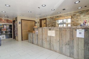 A reception desk with a wooden finish, a stone wall, and a tiled floor. - Zion Pioneer Lodge (Springdale)