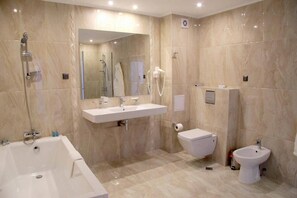 Une salle de bain moderne équipée d’une baignoire, d’un lavabo, de toilettes et d’un bidet.