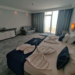 Une chambre d’hôtel avec un lit, un canapé, un bureau et une grande fenêtre.