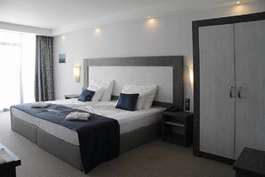 A modern hotel room with a large bed, bedside tables, a wardrobe, and a window with curtains. - Hotel Moonlight Path (Nessebar)