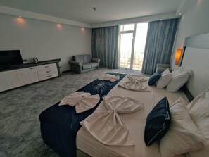 Une chambre d’hôtel avec un lit, un canapé, une télévision et un bureau.