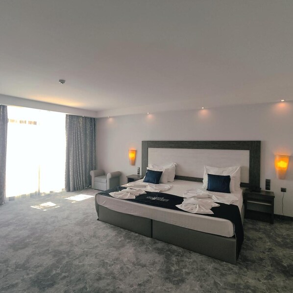A modern hotel room with a large bed, two bedside tables, a chair, and a large window with curtains. - Hotel Moonlight Path (Nessebar)