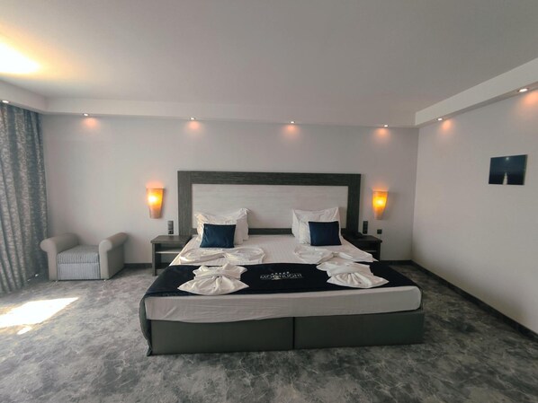Une chambre d’hôtel avec un grand lit, deux tables de chevet, une chaise et des lampes fixées au mur.