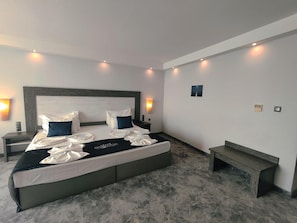 Habitació d'hotel moderna amb un llit gran, taules de nit, una panxa i un calaixer.