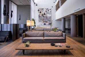 Eine moderne Lobby mit einer Couch, einem Couchtisch, Pendelleuchten und einem großen abstrakten Gemälde.
