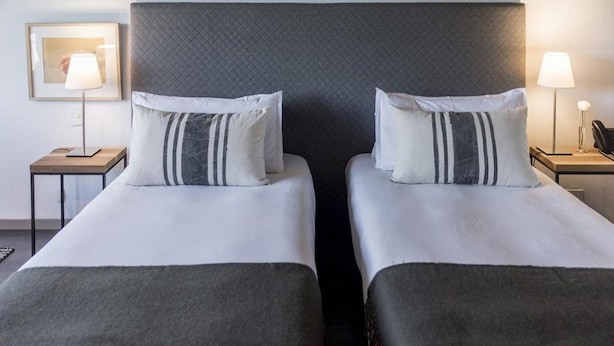 A hotel room with two beds, each with a pillow and a bedside table with a lamp. - Casasur Pilar Hotel (La Lonja)