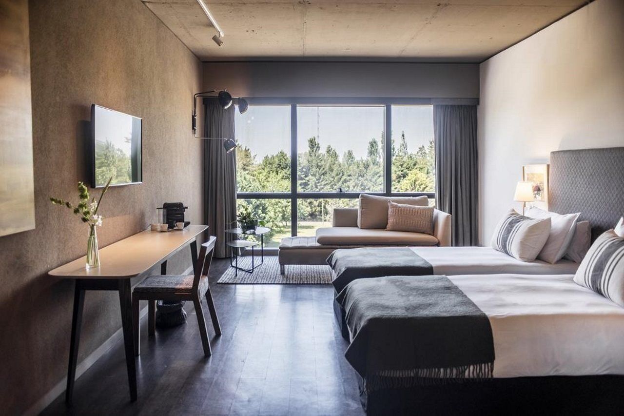 Une chambre d’hôtel moderne dotée d’une grande fenêtre, d’un bureau, de deux lits et d’un canapé.