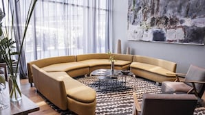 A modern living room with a curved sofa, a coffee table, and a patterned rug. - Casasur Pilar Hotel (La Lonja)