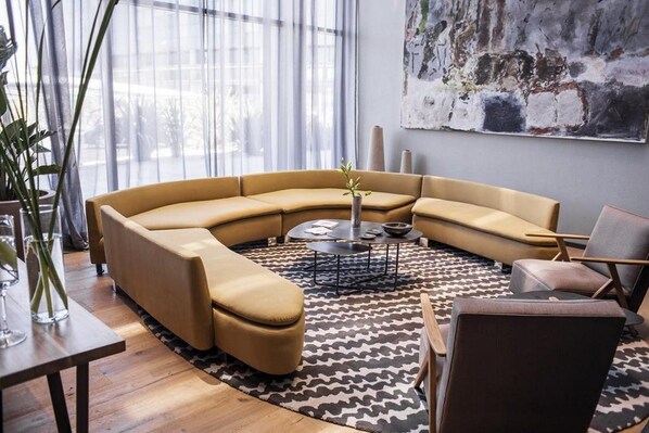 Uma sala de estar moderna com um sofá curvo, uma mesa de centro e um tapete estampado.