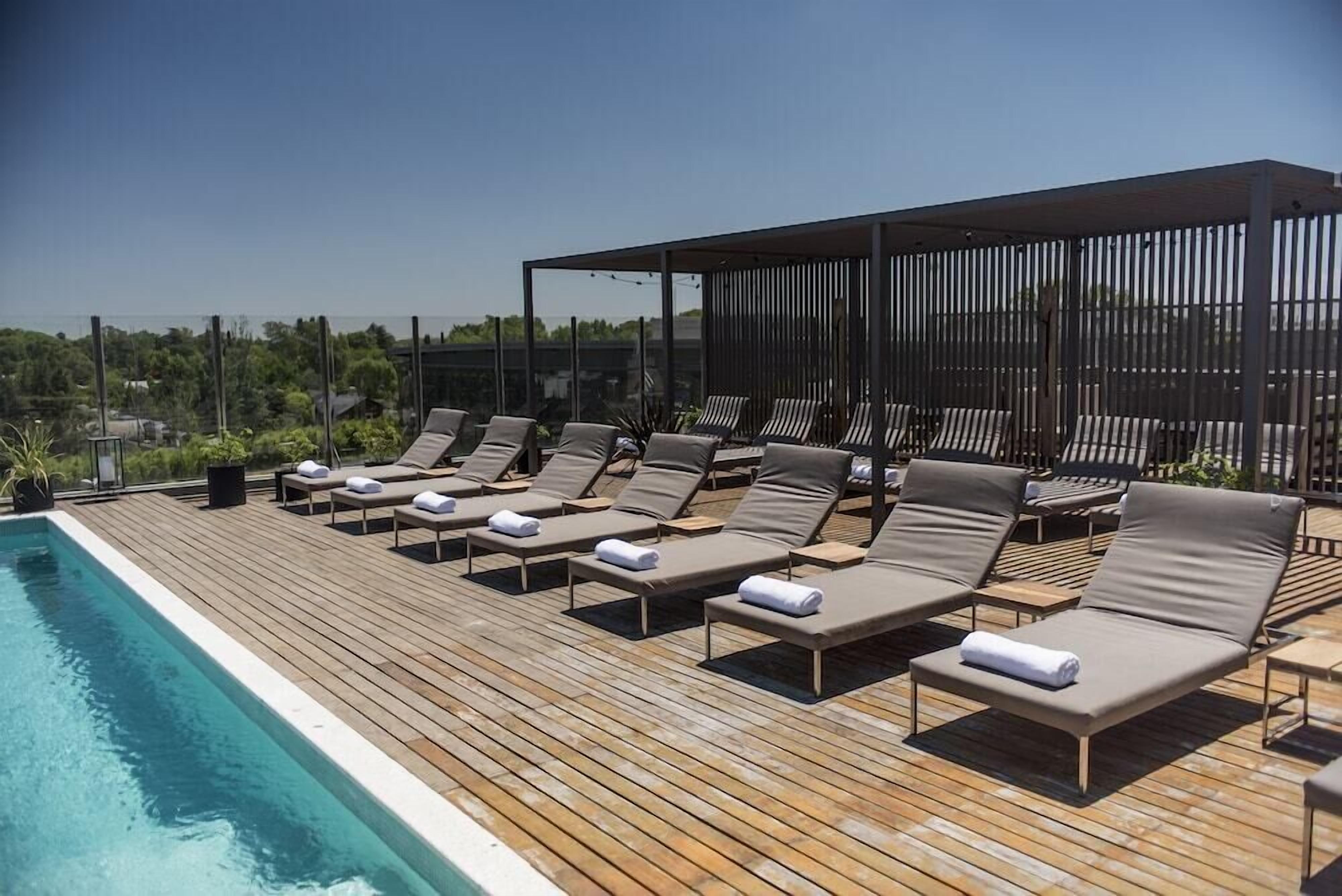 A rooftop pool area with lounge chairs and a wooden deck.