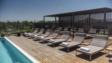 A rooftop pool area with lounge chairs and a wooden deck.