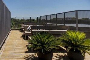 Eine Dachterrasse mit Holzboden, Sitzbereichen und Topfpflanzen.