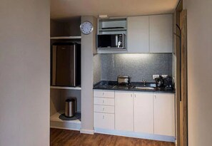 A compact kitchen with a stainless steel refrigerator, microwave, and toaster. - Casasur Pilar Hotel (La Lonja)