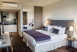 Ein Hotelzimmer mit Bett, Nachttisch, Lampe und einer Küchenzeile.