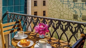 Un balcone con tavolo in legno, due sedie, un vaso di fiori e una mappa appesa al muro.