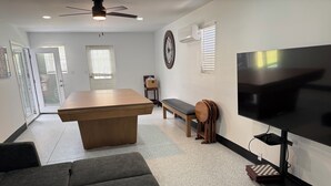 A modern living room with a wooden coffee table, a grey sofa, a TV, and a ceiling fan. - Cozy 1-bedroom cottage in serene Ravenel with AC (Ravenel)
