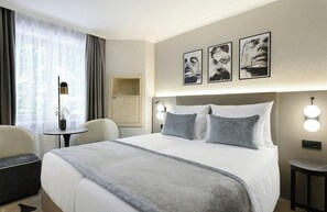 A hotel room with a large bed, bedside lamps, a small table, a chair, and a cabinet. - Intercityhotel Magdeburg (Magdeburg)