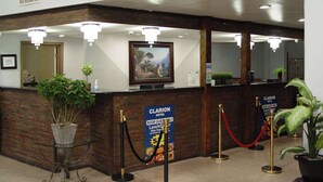 A hotel reception desk with a framed picture, a potted plant, and a sign indicating room guest-only access. - Clarion Hotel Bakersfield North (Bakersfield)