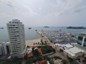 A coastal marina with boats, a beach, and a tall building. - New studio apartment in front of the marina! (Santa Marta)