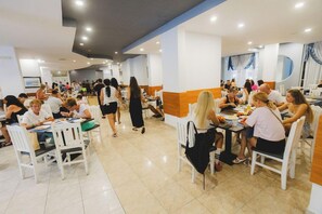 A spacious dining area with multiple tables and chairs, a central walkway, and a modern interior design. - Sun Palace Hotel - All Inclusive (Nessebar)