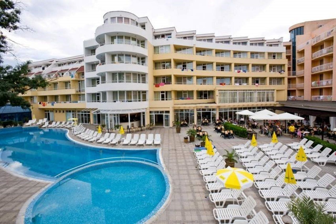 Ett hotell med pool, solstolar och ett takförsett utomhusområde.