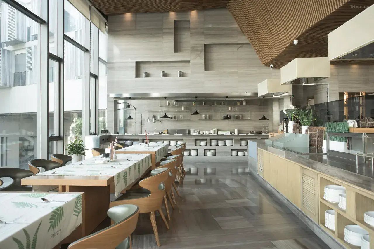 A modern kitchen with a central island, long dining tables, and chairs.