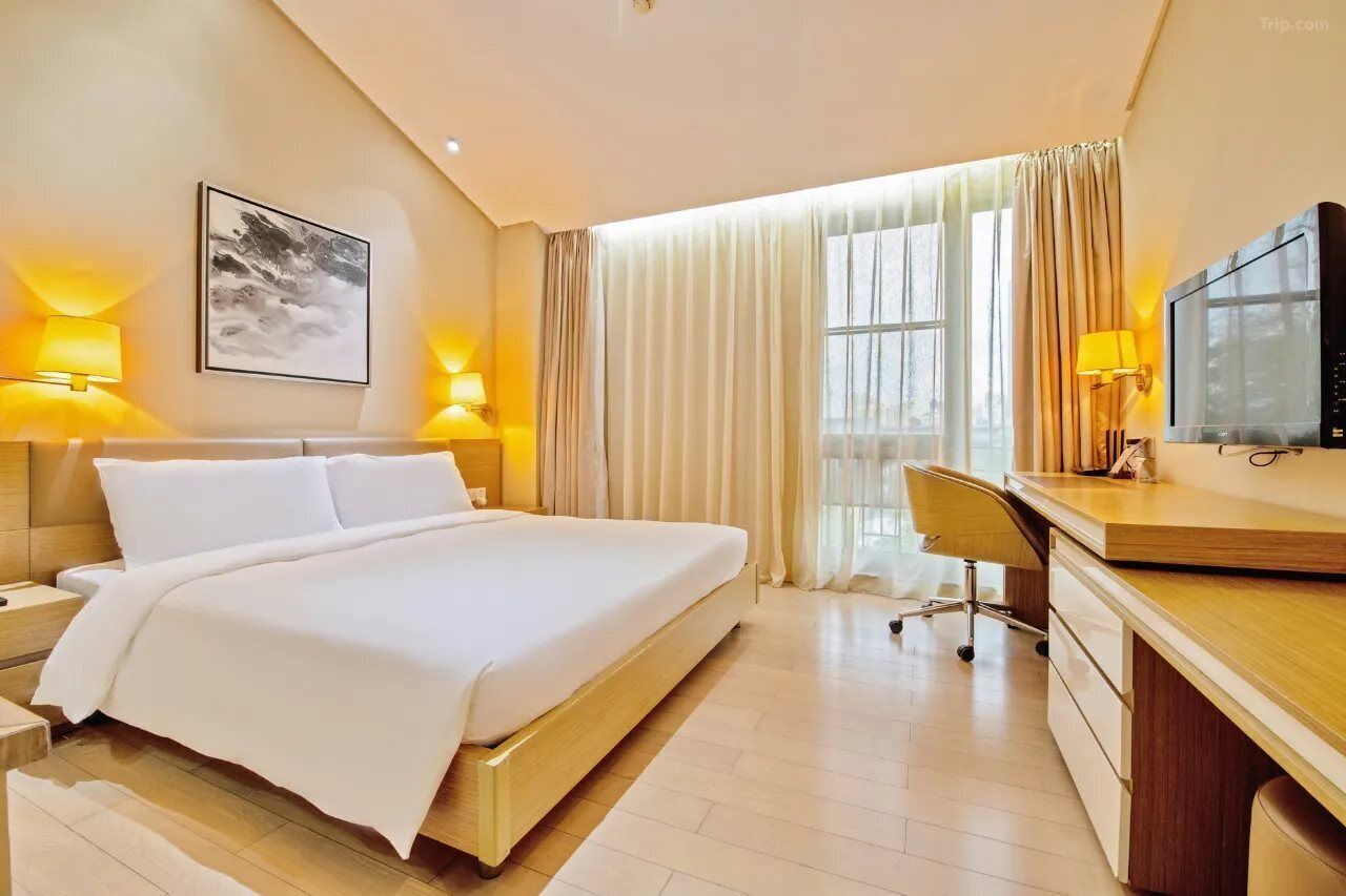 Habitación de hotel con cama, escritorio, silla, televisor y obras de arte.