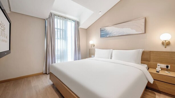 A modern hotel room with a large bed, a ceiling light, a wall-mounted artwork, and a window with curtains. - CM+ Serviced Apartment Shenzhen Hillside (Shenzhen)