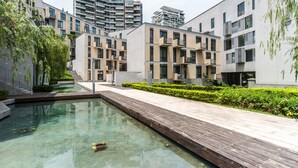 A modern residential building with a swimming pool, wooden deck, and well-maintained greenery. - CM+ Serviced Apartment Shenzhen Hillside (Shenzhen)