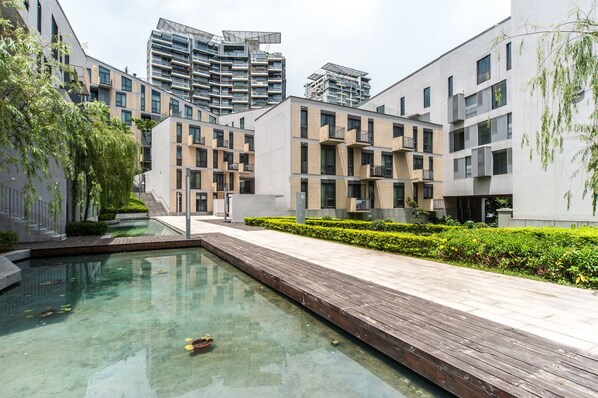 A modern residential building with a swimming pool, wooden deck, and well-maintained greenery. - CM+ Serviced Apartment Shenzhen Hillside (Shenzhen)