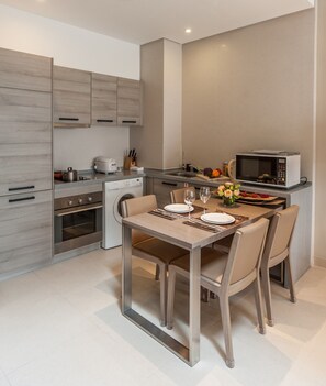 A modern kitchen with a dining area, including a table set for two, a microwave, and a sink. - CM+ Serviced Apartment Shenzhen Hillside (Shenzhen)