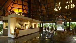 A spacious lobby with a reception desk, a high ceiling with exposed beams, and a central seating area with a reflective floor. - Diani Reef Beach Resort and Spa (Diani Beach)