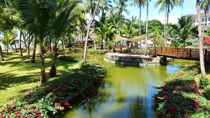 A tropical resort with a central water feature, palm trees, and a wooden bridge. - Diani Reef Beach Resort and Spa (Diani Beach)