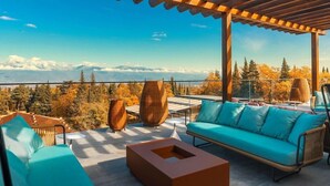 A terrace with a wooden pergola, outdoor furniture, and a view of a mountainous landscape.