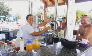 Una zona de bar con mostrador, botellas y una persona sirviendo una bebida.