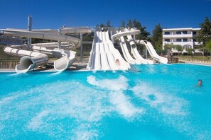 Une piscine avec plusieurs toboggans et un bâtiment en arrière-plan.