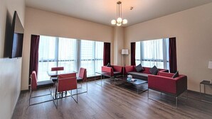 A spacious room with a sofa set, a dining table, and chairs. - Adagio Fujairah (Al-Fujairah)