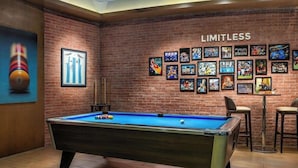A pool table in a room with a brick wall and a 'LIMITLESS' sign. - Adagio Fujairah (Al-Fujairah)