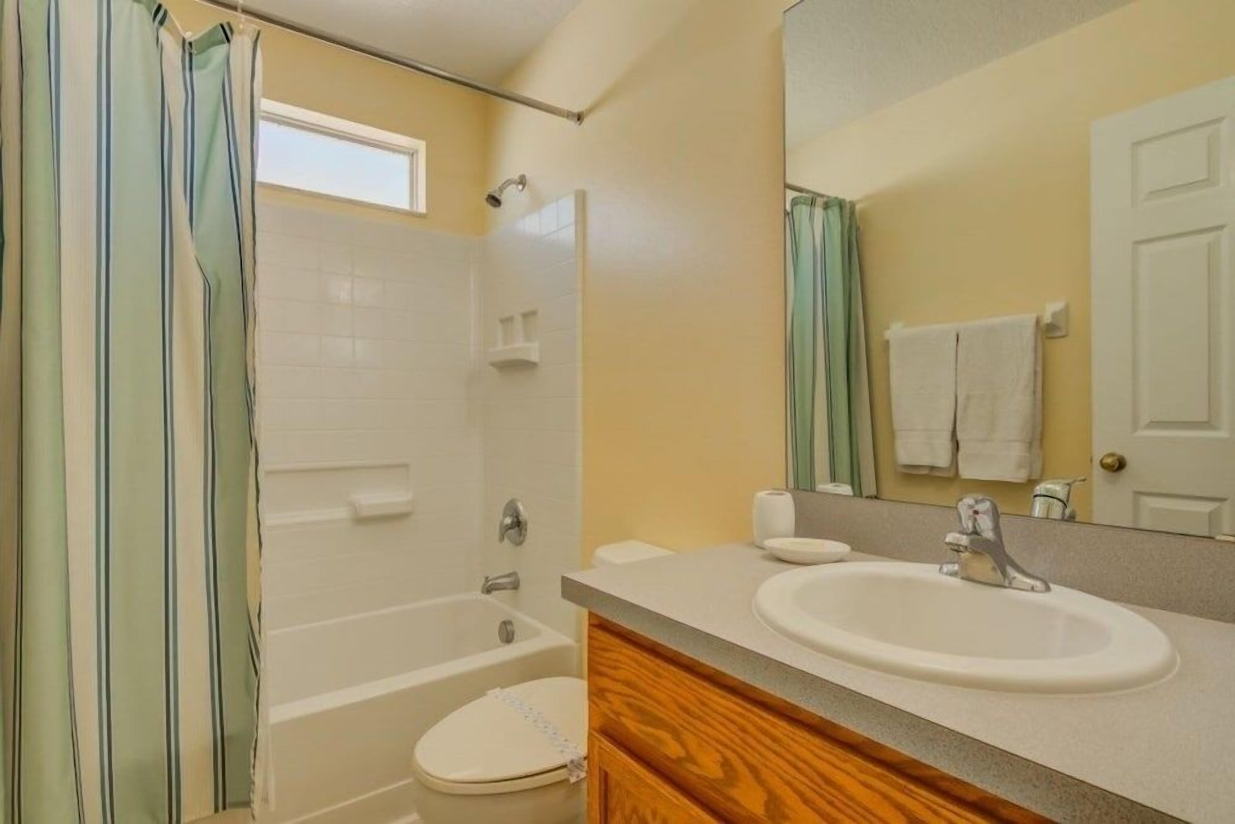 Ein Badezimmer mit einer Badewanne, Toilette, Waschbecken und einem Spiegel über dem Waschbecken.