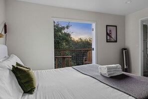 A bedroom with a bed, a view of a balcony, a framed picture, and a heater. - The Retreat at Mount Taylor, by Vinifera Homes (Santa Rosa)