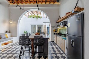 A modern kitchen with a checkered floor, a central island with bar stools, a refrigerator, and a hanging light fixture. - Casa Paguro | A Charming Republican Oasis | 6 (Santa Marta)