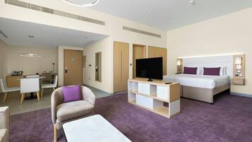A hotel room with a bed, a TV, a desk, a chair, and a sofa.