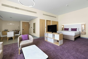 A hotel room with a bed, a TV, a desk, a chair, and a sofa. - Premier Inn Dubai Ibn Battuta Mall (Dubai)