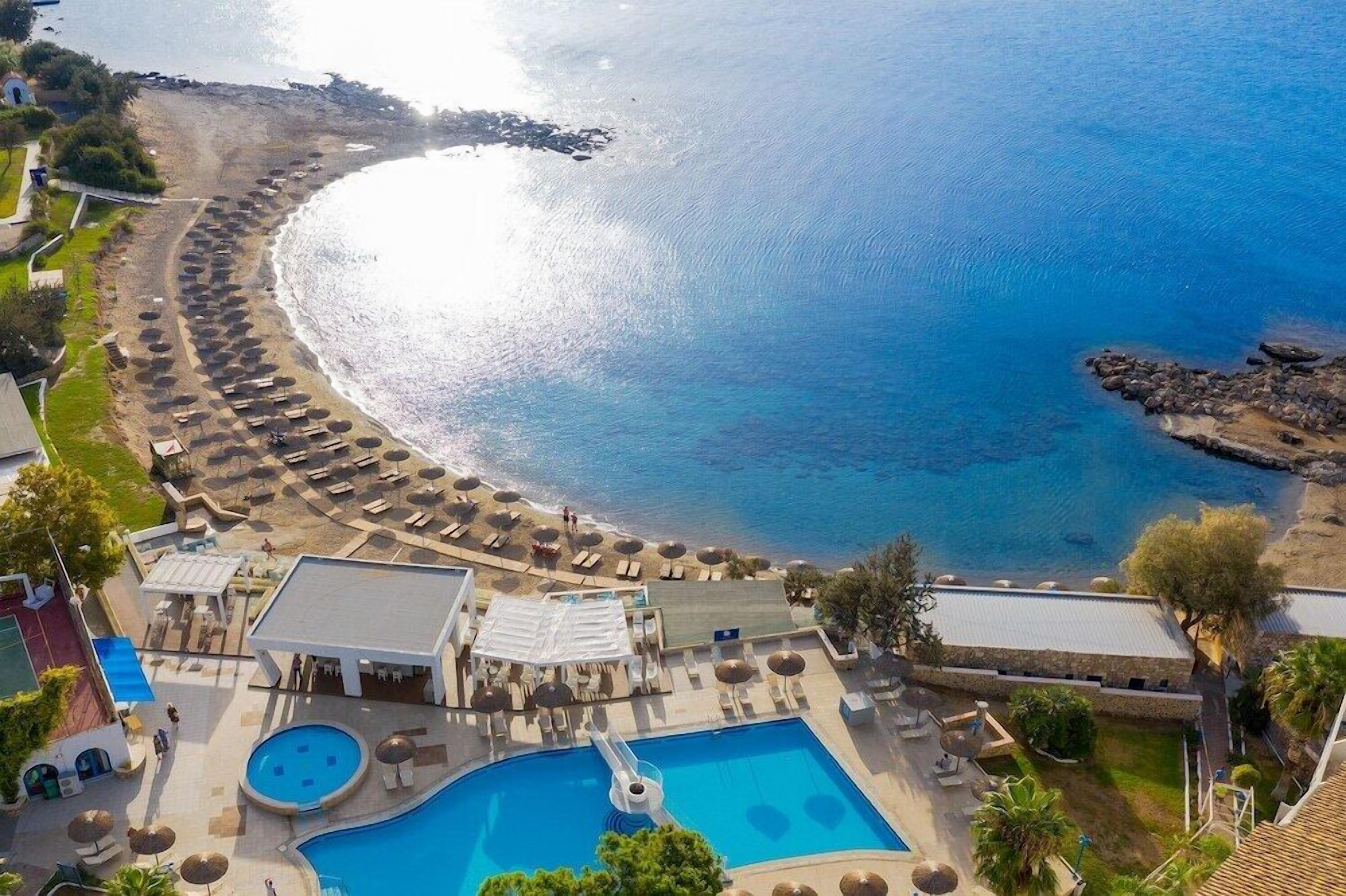 A resort with a pool, sun loungers, and a beach area.