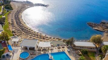 A resort with a pool, sun loungers, and a beach area.